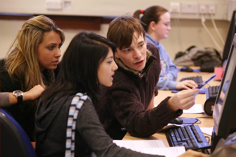 three students studying together at a computer