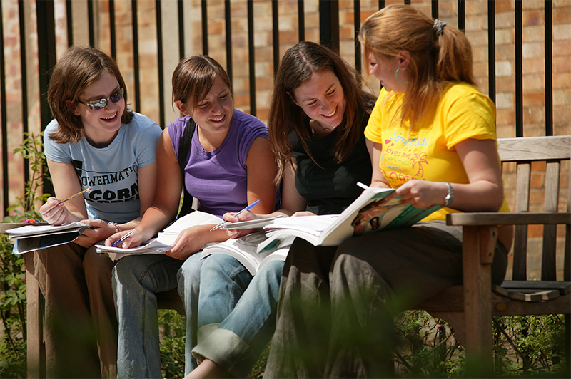 four students sitting on a bench