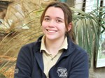 Picture of Rebecca Lewis in uniform at chester zoo sitting in front of tropical enclosure