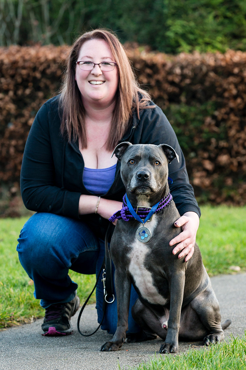 dog sitting with owner crouching behind