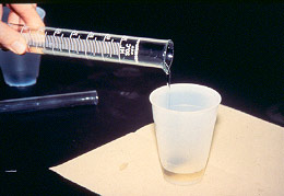 fluid poured from measuring cyclinder into container 1